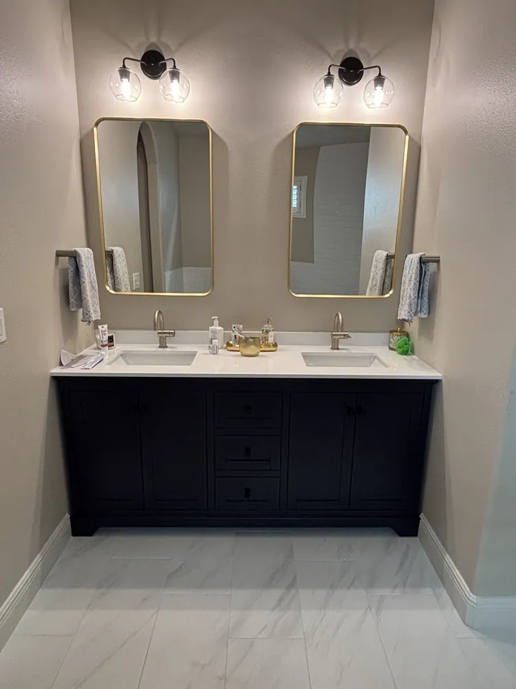 Navy double vanity with white quartz top, gold-framed mirrors and matching sconces